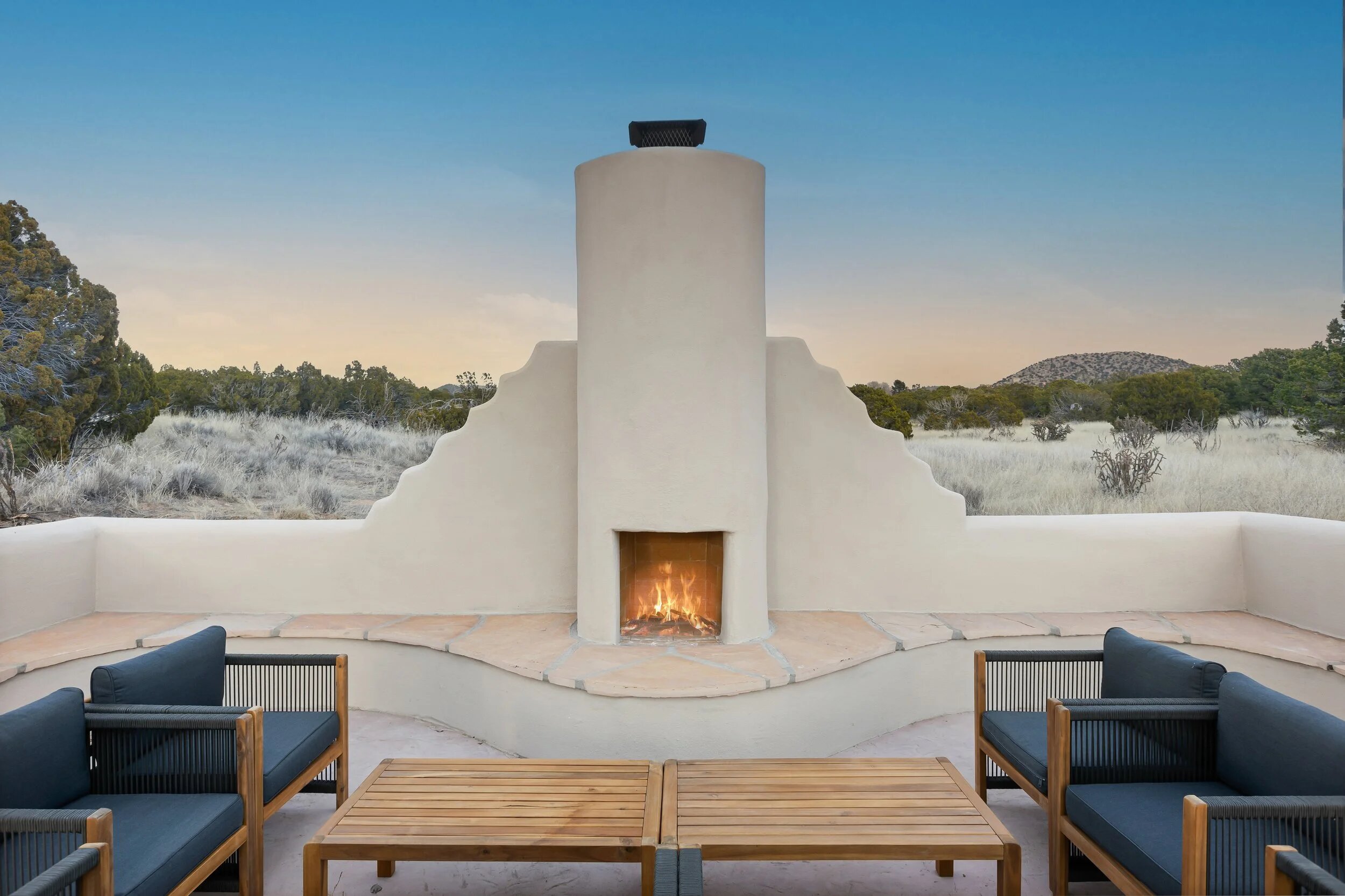 Casa de Camino outdoor adobe fireplace at dusk overlooking the high desert